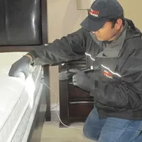 Bed bug inspection technician checking a mattress and bed frame for signs of infestation in Charleston, SC