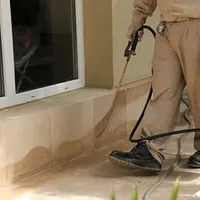 General pest control technician spraying exterior perimeter around a home in Charleston, SC
