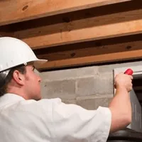 Termite inspection technician checking a basement wall and framing for termite activity in Charleston, SC